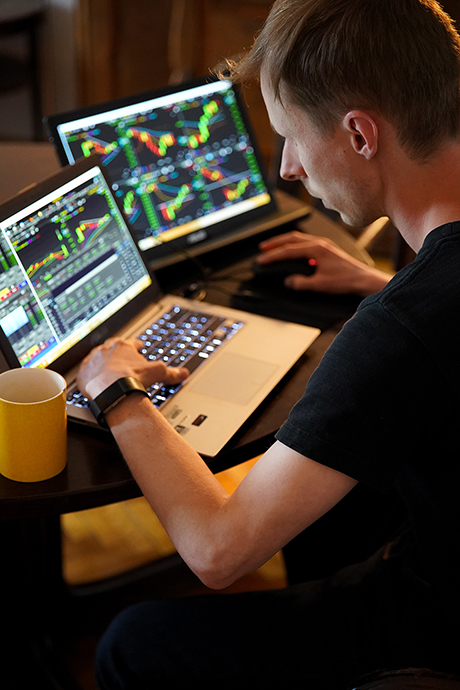 A forex trader using MT4 software on a laptop